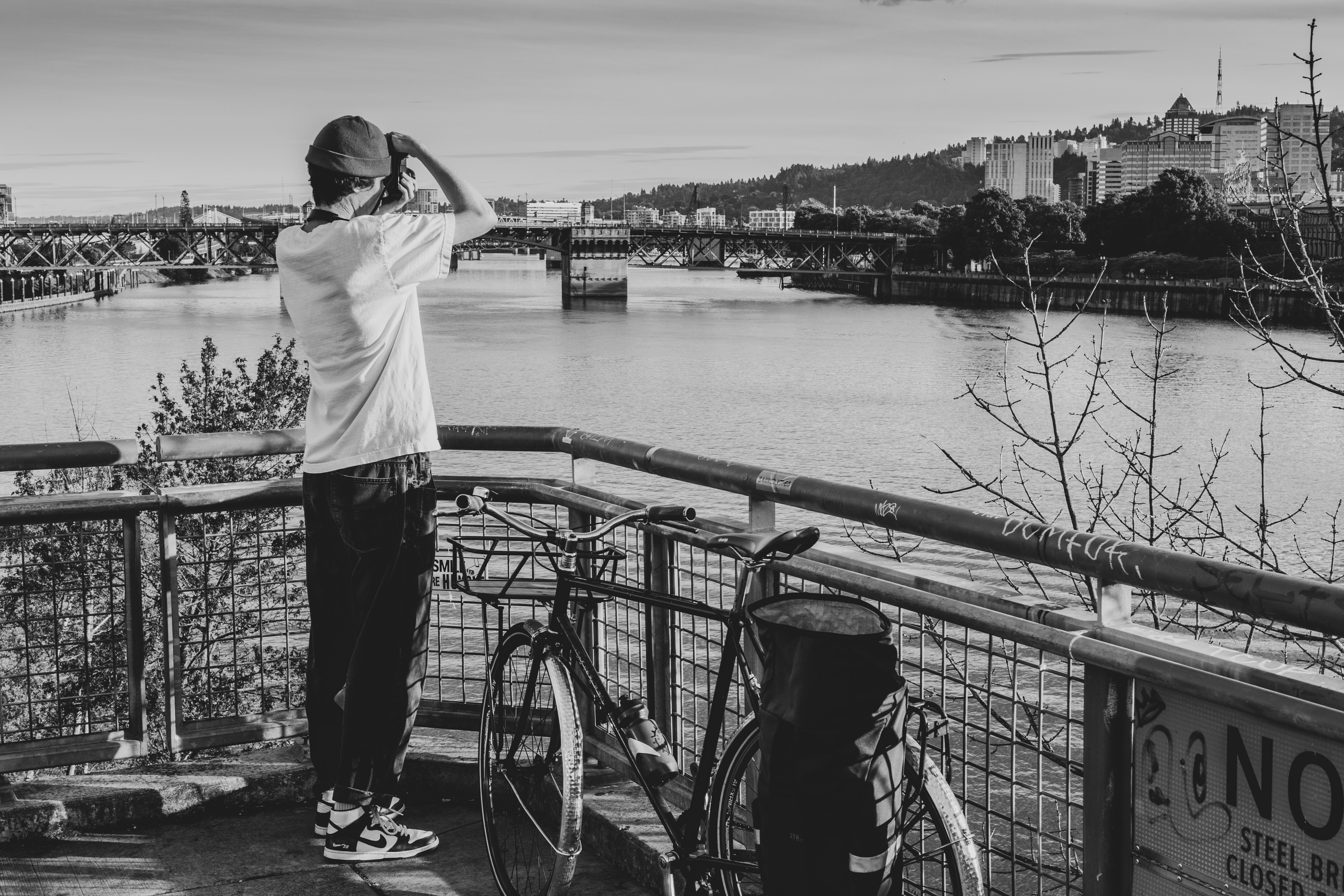 man in white shirt and black pants standing on bridge